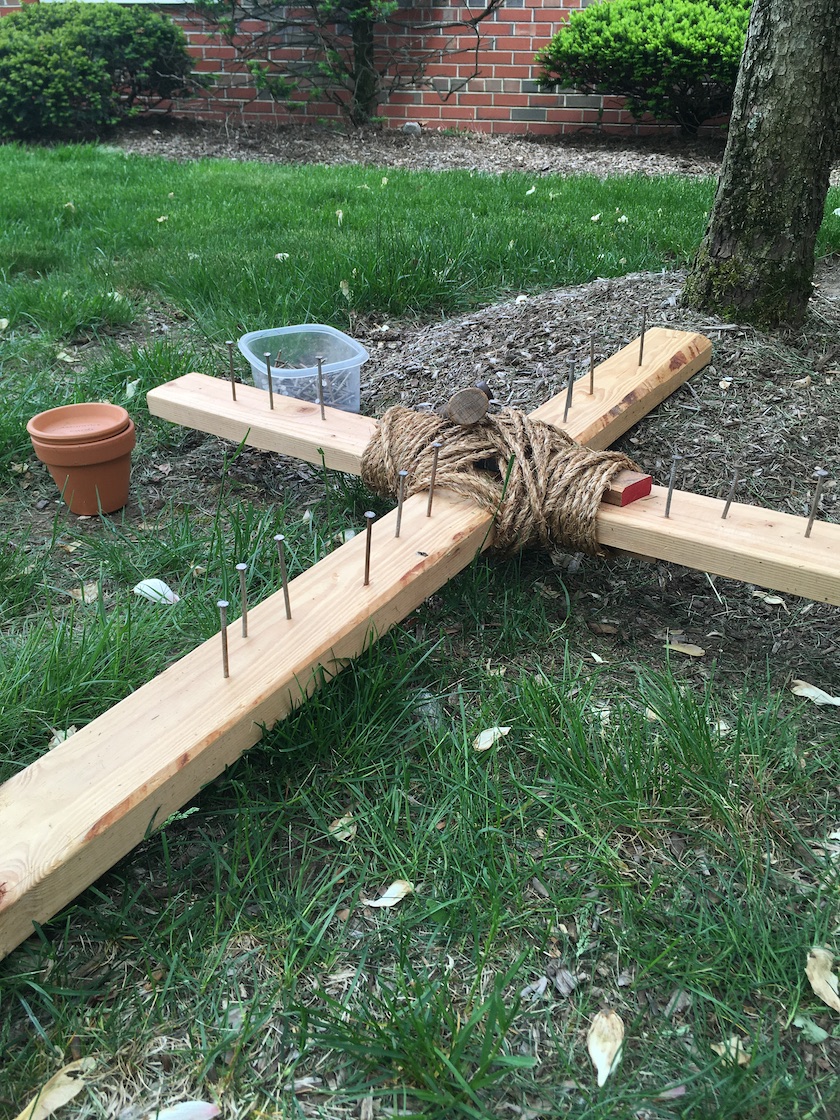 Wooden cross with nails on grass